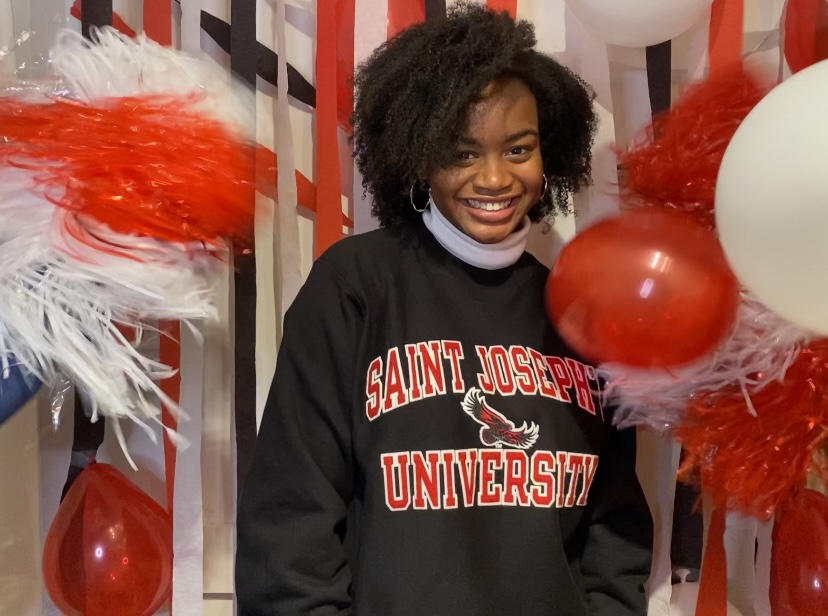 GLC graduate Sheridan Leak poses in a Saint Joseph's University sweatshirt in front of streamers and balloons